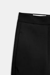 Pantalón de tiro alto con pernera ancha y pinzas delanteras. Cuenta con bolsillos laterales ocultos en la costura y cierre frontal con cremallera, botón interior y gancho.