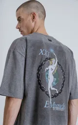 Remera de corte oversize color gris melange, con cuello redondo y mangas cortas. Presenta un estampado en la espalda inspirado en la carta del tarot 'El Mundo', con diseño gráfico detallado y tipografía alusiva.
