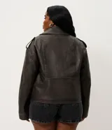 Campera estilo biker de poliuretano color marrón oscuro con efecto lavado, corte oversized, cuello con solapa, cierre frontal asimétrico y bolsillos con cierre.