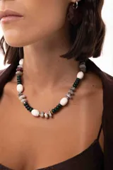 Collar corto elaborado con una combinación de cuentas de piedras naturales, cristales checos y cuentas reconstituidas en tonos blanco, verde oscuro y gris. Cuenta con un cierre de cadena de acero quirúrgico ajustable.