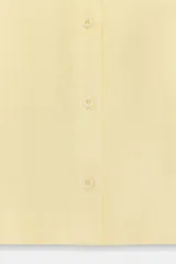 Camisa de manga corta confeccionada en tejido de ramio color blanco. Posee cuello solapa, cierre frontal con botones y detalle de lazos en el acabado de las mangas.