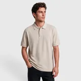 Remera polo de piqué color beige, de manga corta, con cuello clásico, cierre frontal con botones y detalle de logo bordado sutil en el pecho.