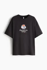 Remera oversized de algodón color negro, con cuello redondo y diseño estampado en el frente de una taza de café junto al texto "Quotidiana Delizia ROME".