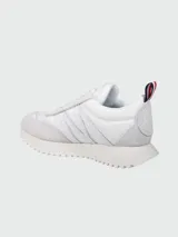Zapatillas Moncler modelo Pacey de color negro, con diseño de caña baja y suela dentada. Presentan detalles en gamuza y nylon, y una presilla trasera con los colores tricolores de la marca.