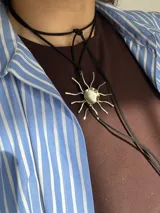 Collar de tiento de gamuza negra con dije de sol irregular hecho a mano en metal plateado.