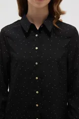 Camisa de poliéster color crema con estampado de pequeños puntos negros, cuello clásico, cierre frontal con botones y mangas largas con puños abotonados.