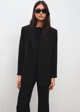 Blazer negro de corte recto, con solapas de muesca, bolsillos con solapa en los laterales y cierre frontal de un botón.