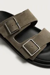 Sandalias de piel con acabado en gamuza, color gris, de diseño plano con plantilla anatómica. Cuenta con dos tiras anchas en el empeine ajustables mediante hebillas metálicas.