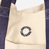 Bolso de mano tipo tote Rip Curl, color beige con detalles en azul marino. Presenta el logo de la marca estampado en el centro y doble asa de hombro.