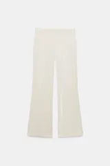 Pantalón flare de tiro alto confeccionado en tejido satinado color negro, con bajo en línea evasé y cierre frontal con cremallera oculta y gancho metálico.