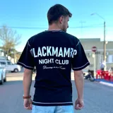 Remera oversize negra con costuras visibles en color blanco, corte holgado y manga corta. Presenta estampado tipográfico en la espalda con el texto "Blackmamba Night Club".