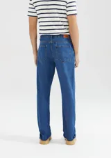 Pantalón de jean de corte slim, color azul clásico, con cierre de botón y cremallera, bolsillos laterales y traseros.