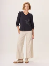 Pantalon de corte ancho y holgado, confeccionado en una mezcla de algodón, viscosa y lino. Presenta un diseño de tiro medio con bolsillos traseros y costuras visibles que recorren el largo de las piernas.