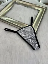 Pack de tres microtangas de encaje con diseño floral, cuentan con tiras laterales regulables y bordes con terminación en cinta elástica. El set incluye una prenda negra, una blanca con estampado floral negro y una beige con estampado floral negro.