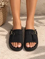 Sandalias de gamuza color tostado, de diseño abierto con tira ancha en el empeine decorada con una hebilla metálica y flecos colgantes.
