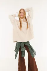 Sweater oversize de punto con diseño de trenzas y rombos en relieve, cuello redondo y mangas largas. Presenta un acabado con efecto lavado en tono beige.