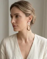 Caravanas colgantes de diseño geométrico irregular, compuestas por dos eslabones entrelazados, uno en tono blanco y otro en baño de oro rosa.