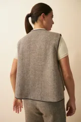 Chaleco color beige con textura tipo espiga, corte holgado y solapa cruzada.