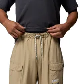 Pantalón convertible Columbia modelo Acker Rock Convert, color beige, de corte holgado y diseño cargo con múltiples bolsillos, bolsillos laterales con solapa y parche de la marca. Las perneras se desmontan mediante cremalleras para convertirlo en short.