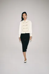 Chaqueta de estilo militar de ZARA Woman Collection, confeccionada en mezcla de algodón en color blanco y beige. Presenta cuello subido, manga larga con puños anchos en contraste y cierre frontal con alamares y botones metálicos en relieve. Tiene bajo asimétrico con abertura en la espalda.
