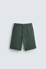 Bermuda tipo jorts de algodón color verde oscuro, con corte relajado y tiro medio. Presenta bolsillos frontales y bolsillos traseros de plastrón.