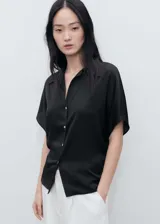 Camisa negra de tejido satinado, manga corta, cuello camisero y cierre frontal con botones.
