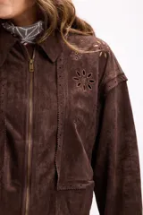 Campera de gamuza color beige con diseño de calados florales en hombros y espalda, cierre frontal y cuello camisero. Presenta un corte relajado y textura suave.