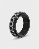 Anillo de acero con diseño central de cadena plateada y bordes negros, estilo moderno y masculino.