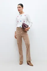 Sweater blanco de punto con bordado de flores azules, rojas y blancas. Tiene cuello redondo y mangas largas.