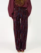 Pantalon de corte recto confeccionado en denim con un acabado desgastado en tonos bordó y azul oscuro. Presenta diseño de cinco bolsillos, cierre frontal con botón y costuras a contratono.