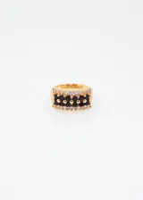 Anillo dorado con tres filas de zirconias negras y dos filas de zirconias blancas.