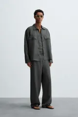 Pantalón de corte relajado confeccionado en tejido de cáñamo color blanco roto. Presenta cintura elástica con cordón interior ajustable, cierre frontal con botones, bolsillos laterales y un bolsillo trasero de plastrón.
