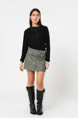 Minifalda gris con textura símil cuero, corte irregular con sobrefalda y cierre frontal con broches metálicos.