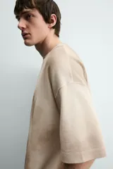 Camiseta de punto de algodón con corte relajado (relaxed fit) y cuello redondo. Presenta un estampado frontal con efecto spray en tonos marrones y beige, y un efecto lavado general.