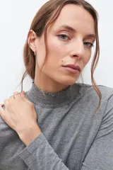Remera gris melange de media polera con punto smock en el cuello y mangas largas.