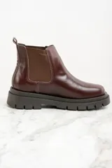 Bota Chelsea de cuero color marrón oscuro con elásticos laterales y suela track negra.