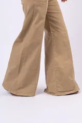 Pantalón wide leg color beige, de tiro medio, con costuras verticales decorativas en el frente y cierre de botón y cremallera.