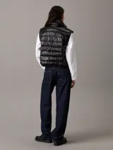 Chaleco puffer negro Calvin Klein Essentials, con cuello alto, cierre de cremallera, bolsillos laterales y logo estampado en el pecho.