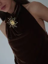 Collar tipo choker con tira de cuero marrón y dije central de sol grande en bronce, con terminación de tira larga y detalle metálico colgante.