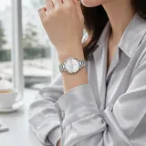 Reloj analógico de mujer con caja redonda y malla de eslabones metálicos en color plateado. Presenta esfera minimalista con índices finos y movimiento de cuarzo japonés.