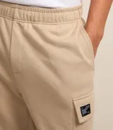 Bermuda masculina color marrón oscuro, confeccionada en tela French Terry, con cintura elástica y cordón de ajuste. Presenta bolsillos cargo funcionales a los lados.