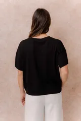 Remera negra de corte oversize con cuello redondo, mangas cortas amplias, hombros caídos y recortes delanteros.