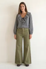 Blusa de corte oversize con estampado de cuadros vichy en blanco y negro. Presenta un cuello con volados, mangas largas con puños elásticos y un cierre frontal con lazo negro.