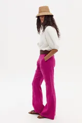 Pantalón de lino fucsia de corte palazzo, tiro medio-alto, pretina ancha, cierre frontal oculto y bolsillos laterales.