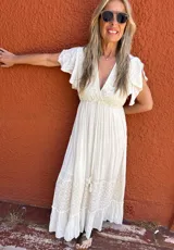 Vestido largo color crudo, de seda con bordados en el mismo tono, escote en V, mangas cortas con volados y corte imperio.