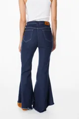 Jean elastizado azul oscuro con diseño de volados en la parte baja de la pierna, ruedo descosido con juego de largos (más largo atrás que adelante).