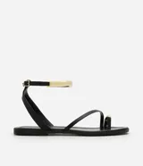 Sandalias planas negras con tira fina en el dedo y pulsera al tobillo con hebilla y aplique dorado.