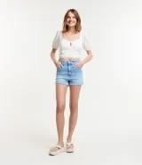 Short de jean celeste, corte hotpants, de cintura alta, con bolsillos delanteros y traseros, cierre con botón y cremallera, y ruedo doblado.