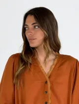 Vestido midi color beige, de corte recto y holgado, con mangas cortas abullonadas, escote en V con solapa abotonada en contraste marrón y tajo lateral en el bajo.