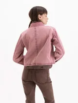 Chaqueta de gabardina color rosado con efecto desgastado, de calce relajado, cuello clásico marrón, bolsillos delanteros aplicados y cierre frontal con broches metálicos a presión.